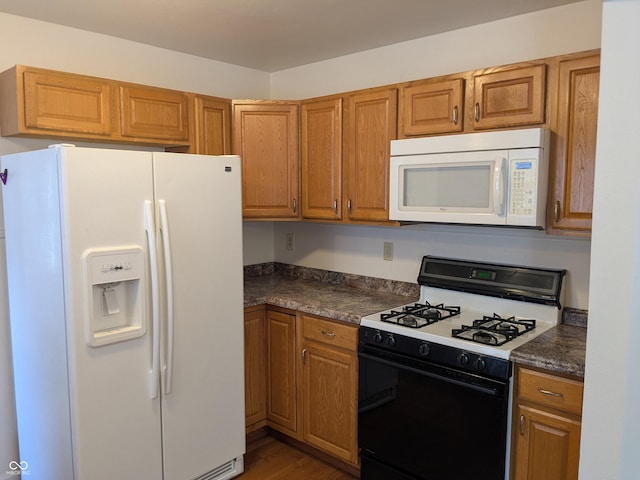 1630 Lawton Ave, Columbus, IN 47201 - kitchen featuring white appliances, dark countertops, brown cabinets, and wood finished floors
