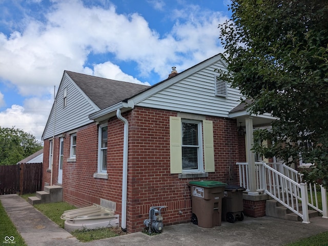 1630 Lawton Ave, Columbus, IN 47201 - view of side of home featuring brick siding, a shingled roof, and a chimney