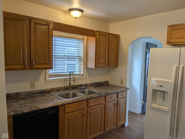 1630 Lawton Ave, Columbus, IN 47201 - kitchen featuring white fridge with ice dispenser, black dishwasher, dark countertops, arched walkways, and dark wood finished floors