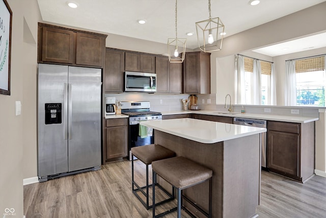 1715 Beyers St, Fortville, IN 46040 - kitchen with appliances with stainless steel finishes, light wood-type flooring, dark brown cabinetry, light countertops, and a peninsula
