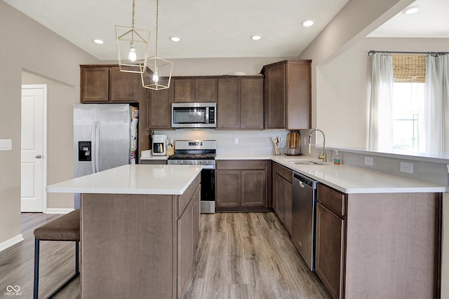 1715 Beyers St, Fortville, IN 46040 - kitchen featuring appliances with stainless steel finishes, light wood-style flooring, a breakfast bar, light countertops, and pendant lighting