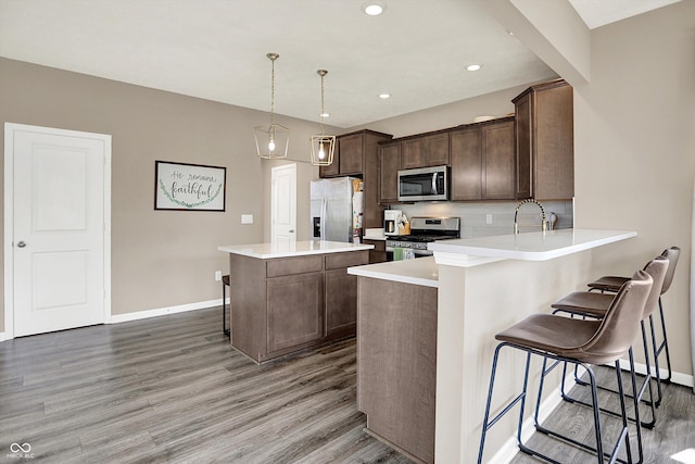 1715 Beyers St, Fortville, IN 46040 - kitchen with light wood-style flooring, appliances with stainless steel finishes, a kitchen breakfast bar, decorative backsplash, and a center island