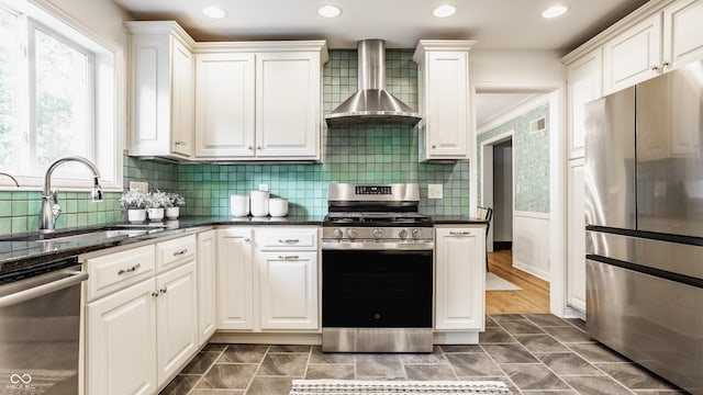 5809 N Washington Blvd, Indianapolis, IN 46220 - kitchen with appliances with stainless steel finishes, wall chimney exhaust hood, white cabinets, tasteful backsplash, and recessed lighting