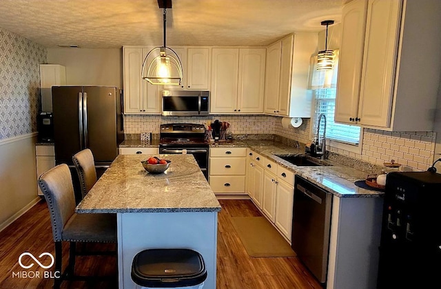 6974 S County Road 400 E, Clayton, IN 46118 - kitchen with appliances with stainless steel finishes, dark wood finished floors, a kitchen island, a breakfast bar area, and decorative light fixtures