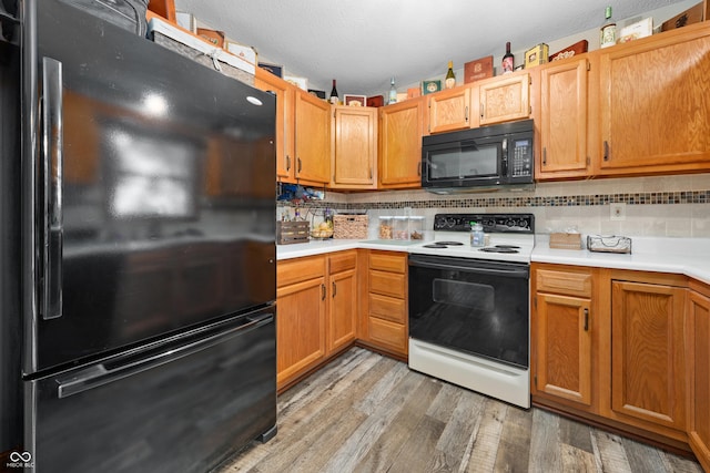 456 Old Hickory Ln, Greenwood, IN 46142 - kitchen featuring black appliances, light countertops, tasteful backsplash, light wood-type flooring, and a textured ceiling