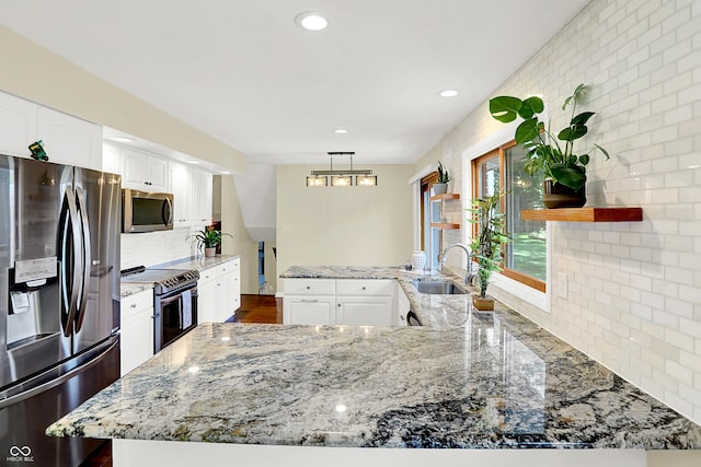 1441 Hunter Pl, Columbus, IN 47203 - kitchen with appliances with stainless steel finishes, a peninsula, light stone countertops, white cabinets, and decorative backsplash