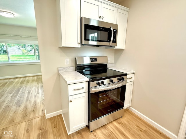 1809 Beam Rd, Columbus, IN 47201 - kitchen with appliances with stainless steel finishes, light wood-style floors, light countertops, and white cabinetry