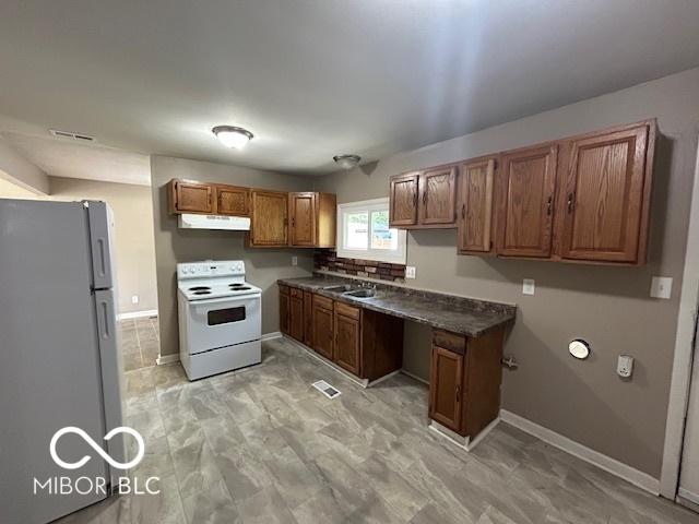 4463 N Bolton Ave, Indianapolis, IN 46226 - kitchen featuring white appliances, under cabinet range hood, brown cabinets, and dark countertops