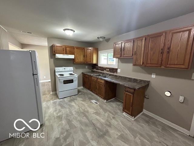 4463 N Bolton Ave, Indianapolis, IN 46226 - kitchen with white appliances, under cabinet range hood, brown cabinets, and dark countertops