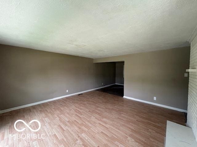4463 N Bolton Ave, Indianapolis, IN 46226 - unfurnished living room with a textured ceiling, wood finished floors, and a fireplace