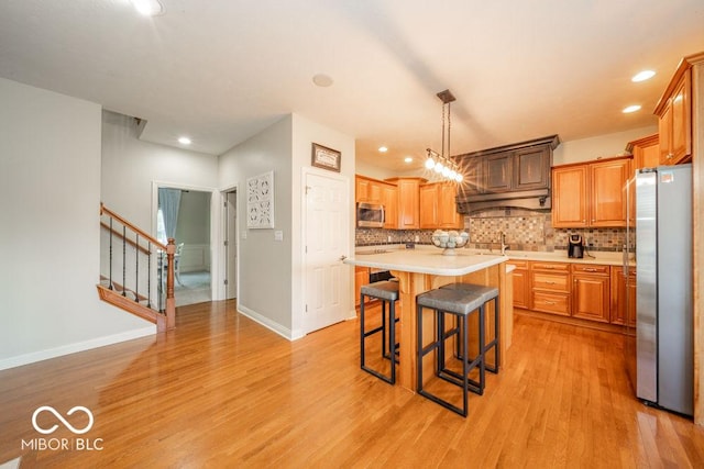 7929 W Bristol Way, New Palestine, IN 46163 - kitchen with appliances with stainless steel finishes, light countertops, light wood-style flooring, decorative backsplash, and a kitchen breakfast bar