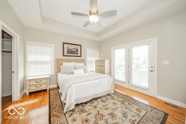 7929 W Bristol Way, New Palestine, IN 46163 - bedroom with access to exterior, a tray ceiling, light wood-style flooring, and ceiling fan
