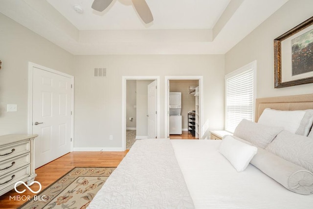 7929 W Bristol Way, New Palestine, IN 46163 - bedroom with light wood-style floors, a tray ceiling, a walk in closet, and a ceiling fan