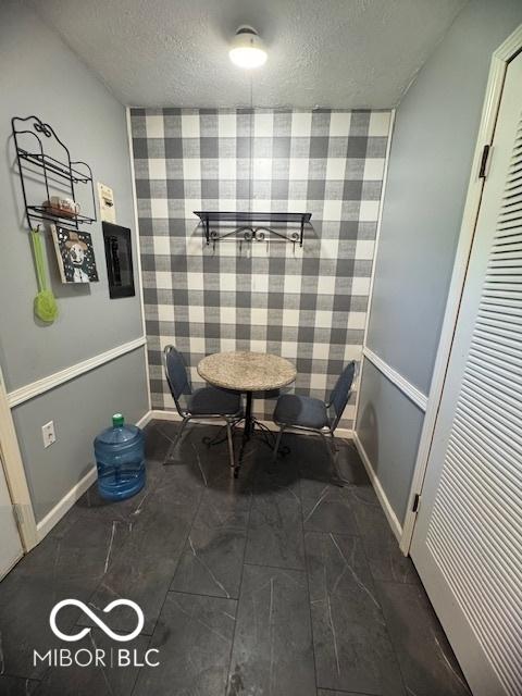 dining area with wallpapered walls, an accent wall, and a textured ceiling