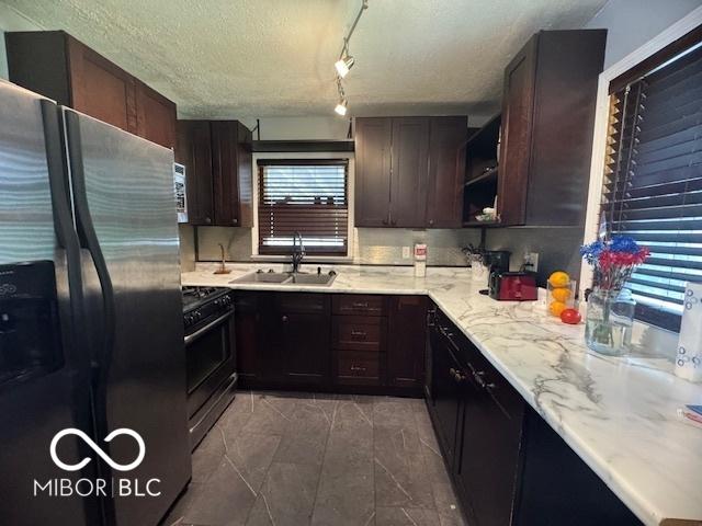 kitchen featuring stainless steel fridge with ice dispenser, black range with gas stovetop, dark brown cabinets, open shelves, and a textured ceiling