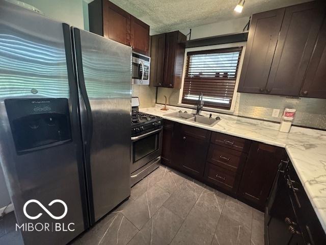 kitchen with appliances with stainless steel finishes, dark brown cabinets, and a textured ceiling