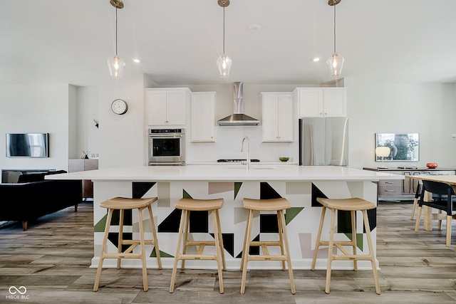 9732 Junction, Fishers, IN 46037 - kitchen featuring light wood-style floors, wall chimney exhaust hood, light countertops, an island with sink, and recessed lighting