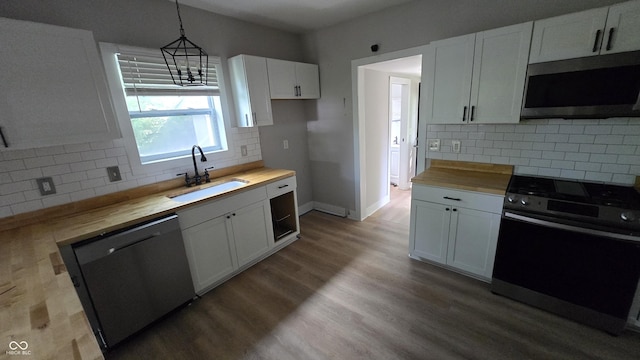 1805 S Denny St, Indianapolis, IN 46203 - kitchen featuring stainless steel appliances, butcher block counters, decorative backsplash, white cabinetry, and decorative light fixtures