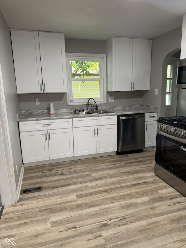 67 N Devon Ave, Indianapolis, IN 46219 - kitchen with appliances with stainless steel finishes, arched walkways, and white cabinetry