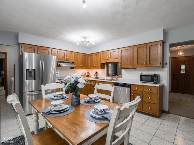479 Raintree Dr, Danville, IN 46122 - kitchen with stainless steel appliances, under cabinet range hood, light countertops, backsplash, and brown cabinets