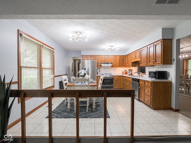 479 Raintree Dr, Danville, IN 46122 - kitchen featuring stainless steel appliances, under cabinet range hood, brown cabinets, a textured ceiling, and light countertops