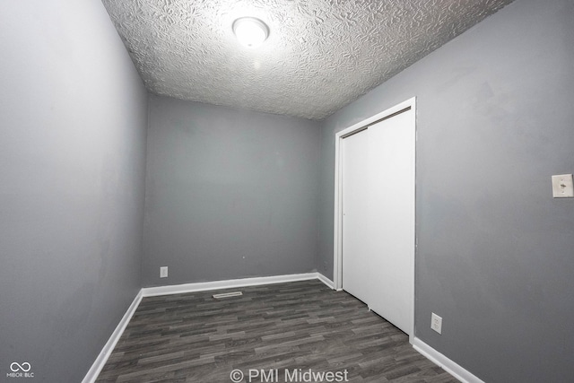 5737 E 22nd St, Indianapolis, IN 46218 - unfurnished bedroom featuring dark wood-type flooring, a closet, and a textured ceiling