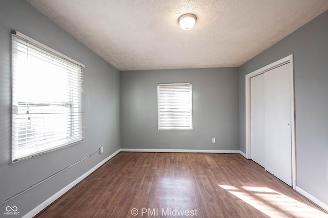 5737 E 22nd St, Indianapolis, IN 46218 - unfurnished bedroom featuring wood finished floors, multiple windows, a closet, and a textured ceiling
