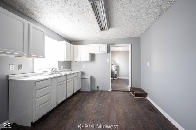 5737 E 22nd St, Indianapolis, IN 46218 - kitchen featuring dark wood-style flooring, electric water heater, white cabinets, light countertops, and a textured ceiling