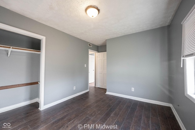 5737 E 22nd St, Indianapolis, IN 46218 - unfurnished bedroom featuring dark wood-type flooring, a textured ceiling, and a closet