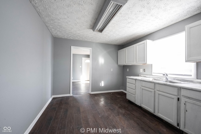 5737 E 22nd St, Indianapolis, IN 46218 - kitchen with dark wood-type flooring, white cabinetry, light countertops, and a textured ceiling
