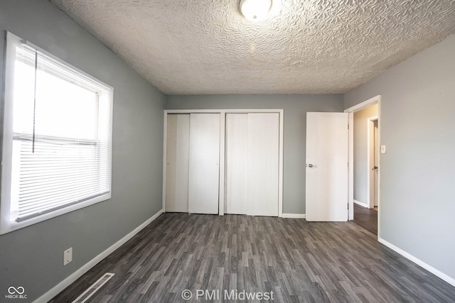 5737 E 22nd St, Indianapolis, IN 46218 - unfurnished bedroom featuring dark wood-style floors, a closet, and a textured ceiling