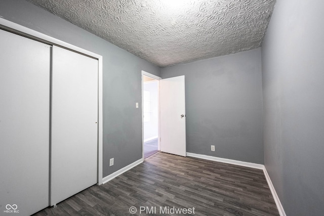 5737 E 22nd St, Indianapolis, IN 46218 - unfurnished bedroom featuring dark wood-style floors, a textured ceiling, and a closet