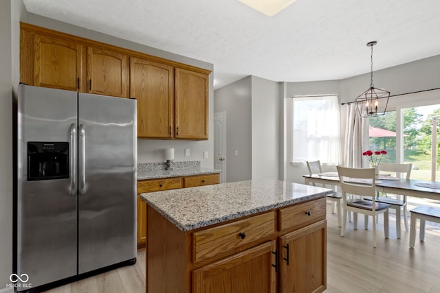 441 Viburnum Run, Westfield, IN 46074 - kitchen featuring stainless steel refrigerator with ice dispenser, light wood finished floors, a chandelier, light stone counters, and brown cabinetry