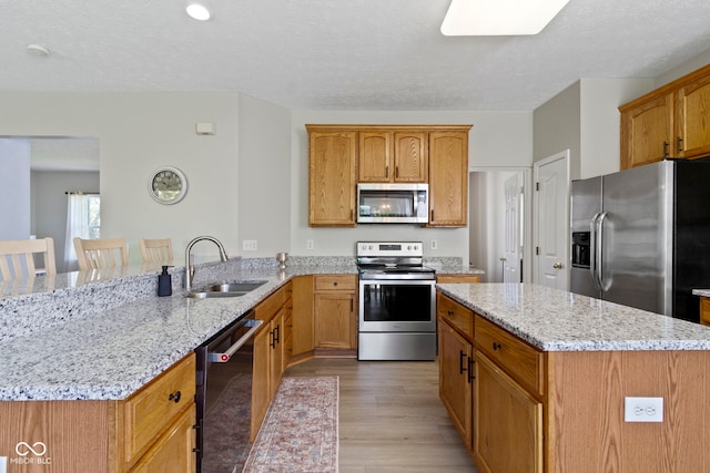 441 Viburnum Run, Westfield, IN 46074 - kitchen featuring stainless steel appliances, a peninsula, light wood-type flooring, light stone counters, and a center island