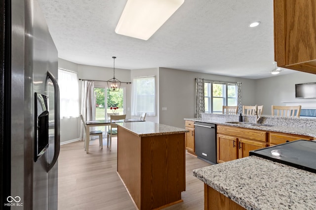 441 Viburnum Run, Westfield, IN 46074 - kitchen with stainless steel appliances, light wood-style flooring, a textured ceiling, brown cabinetry, and a kitchen island