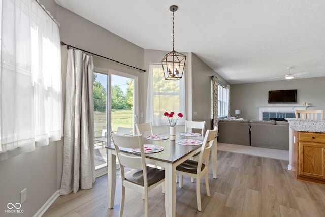 441 Viburnum Run, Westfield, IN 46074 - dining room with light wood-style flooring, a chandelier, a ceiling fan, and a tile fireplace