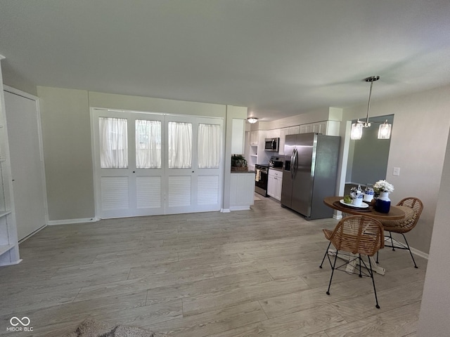 2692 Meadowlark Ln, Columbus, IN 47201 - kitchen with appliances with stainless steel finishes, dark countertops, white cabinetry, hanging light fixtures, and light wood finished floors