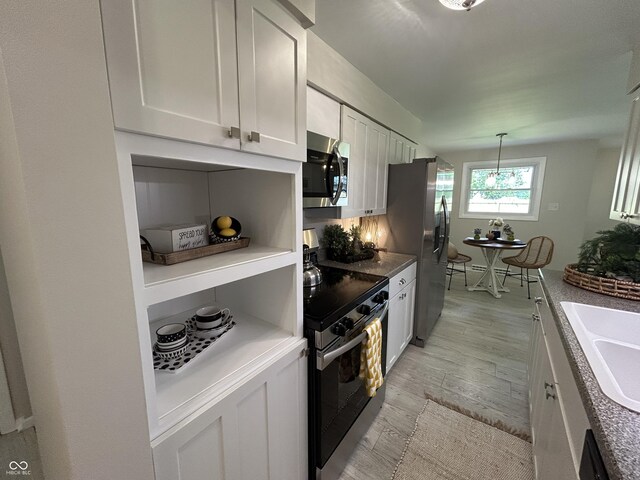 2692 Meadowlark Ln, Columbus, IN 47201 - kitchen with appliances with stainless steel finishes, light wood-type flooring, white cabinets, and decorative light fixtures