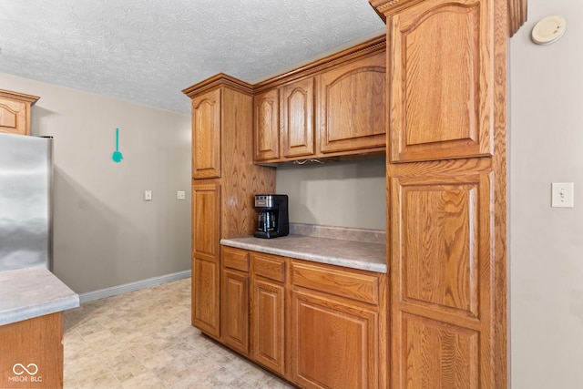 606 S Grange Hall Rd, Hanover, IN 47243 - kitchen with light countertops, stainless steel refrigerator, brown cabinets, and a textured ceiling