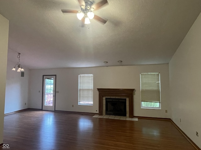 10610 Stillcreek Dr, Indianapolis, IN 46239 - unfurnished living room featuring wood finished floors, a tiled fireplace, a textured ceiling, and a ceiling fan