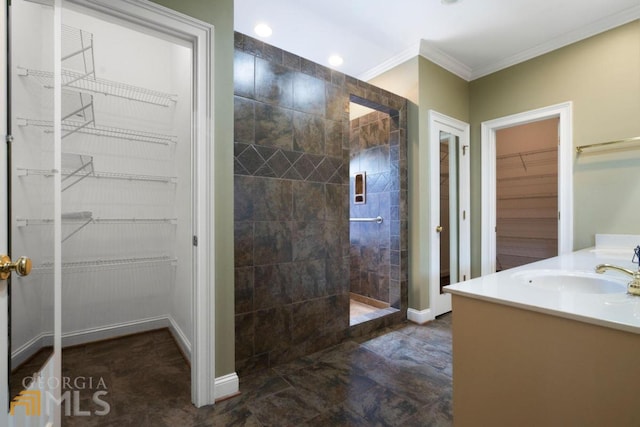 bathroom featuring vanity, tile flooring, a tile shower, and crown molding