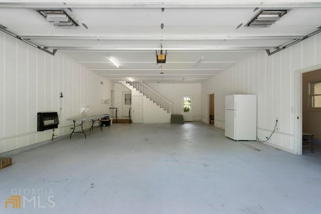 garage with a garage door opener and white fridge