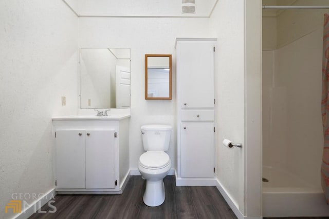 bathroom featuring toilet, oversized vanity, and wood-type flooring