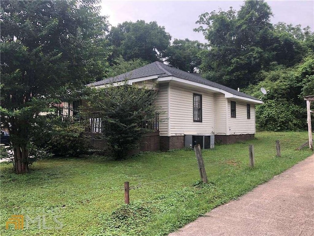 view of side of home with central AC and a yard