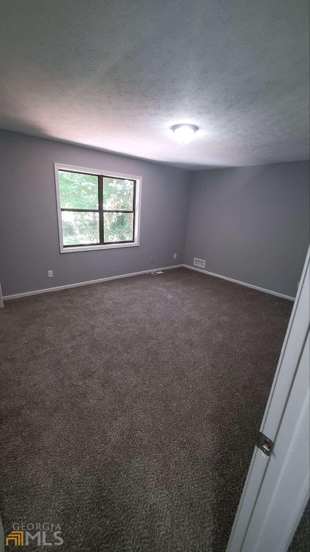 carpeted spare room featuring a textured ceiling