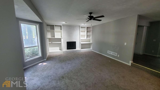 unfurnished living room featuring brick wall, a brick fireplace, ceiling fan, and carpet flooring