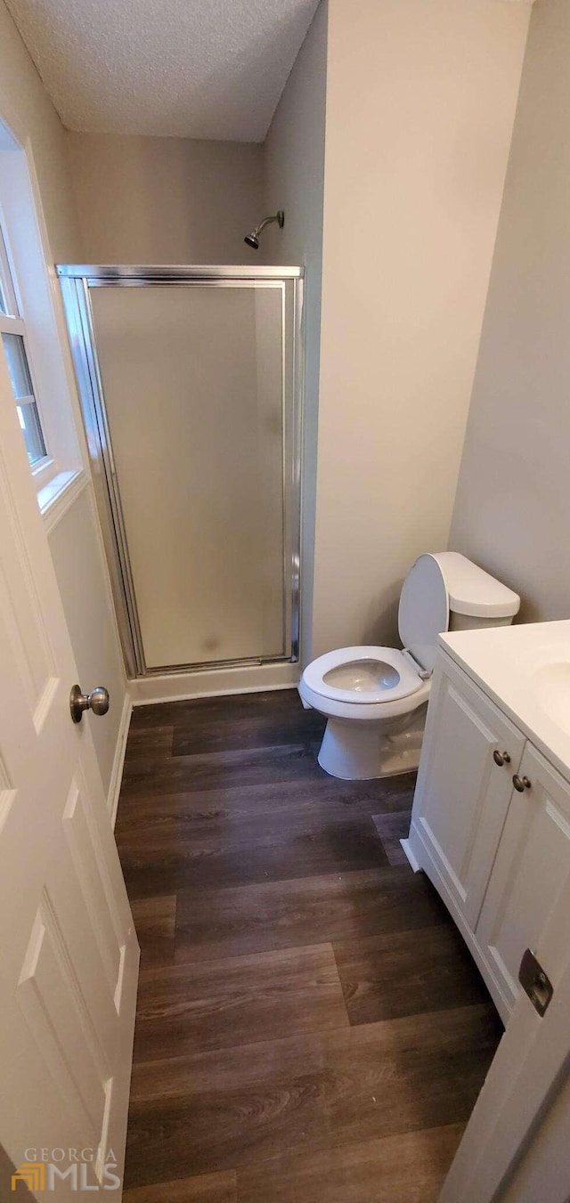 bathroom with walk in shower, toilet, hardwood / wood-style floors, a textured ceiling, and vanity