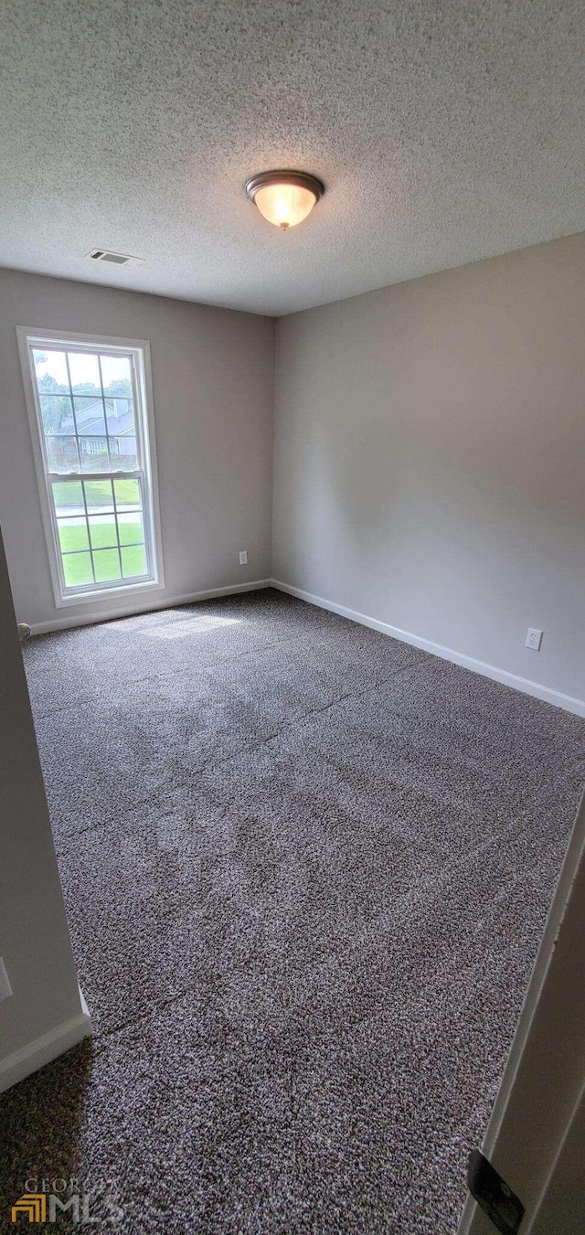 carpeted empty room featuring a textured ceiling