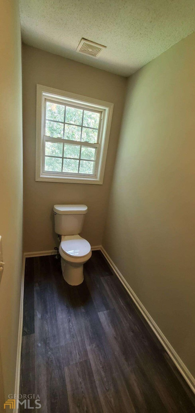 bathroom featuring toilet, a textured ceiling, and hardwood / wood-style flooring