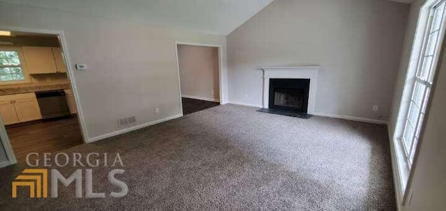 unfurnished living room featuring lofted ceiling and dark colored carpet